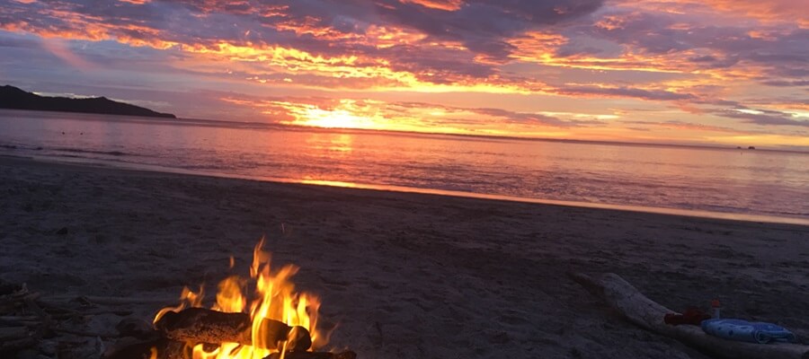 Beautiful orange, yellow and red sunset over Playa Flamingo Costa Rica with fire in the foreground.